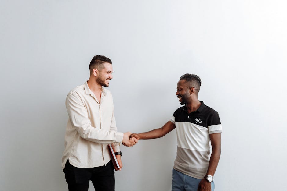 Two smiling professionals making a business agreement with a handshake indoors.