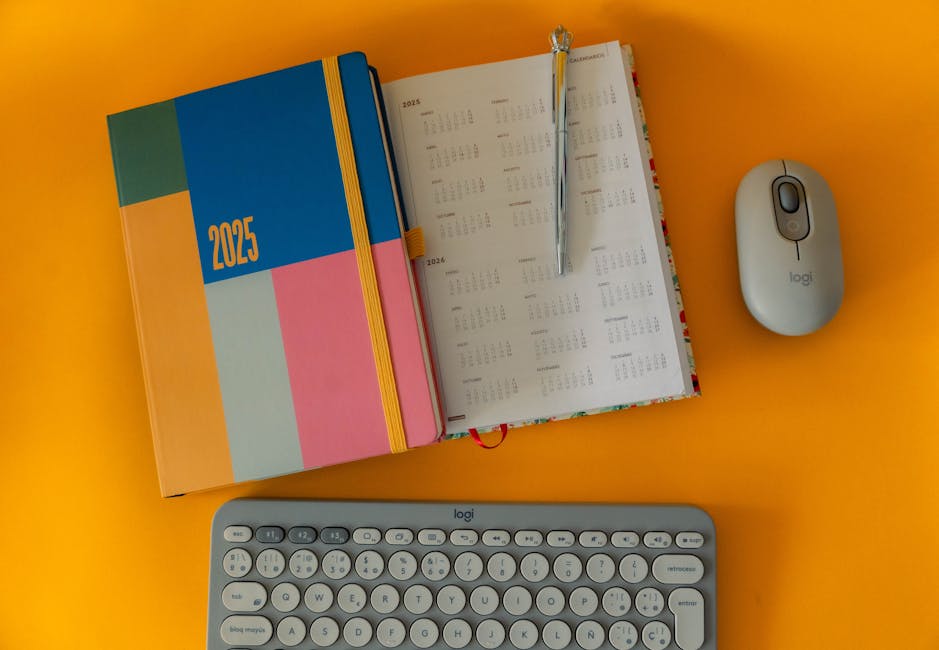 Vibrant 2025 planner with calendar, keyboard, and mouse on orange background.